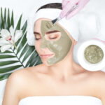The procedure for applying a mask from clay to the face of a beautiful woman. Spa treatments and care of the face in the beauty salon.